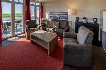 Resort Deichgraf Resort Deichgraf 27-18 Wremen - Wohn-Essbereich mit Couch und Zugang zum Balkon
