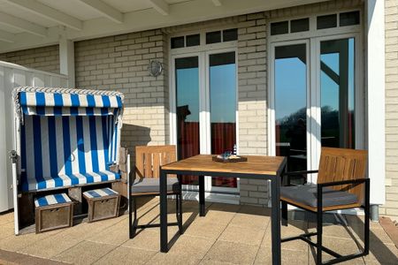 Resort Deichgraf Resort Deichgraf 31-04 Wremen - Überdachte Terrasse mit Strandkorb, Sitzgelegenheit und Grünfläche