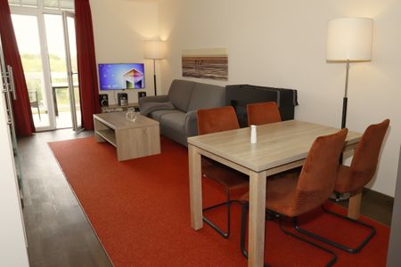 Resort Deichgraf Resort Deichgraf 31-12 Wremen - Wohn-Essbereich mit Couch, Esstisch und Kamin
