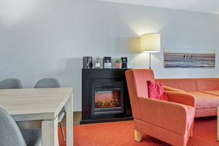 Resort Deichgraf Resort Deichgraf 27-13 Wremen - Wohnbereich mit Sofa, Sessel, Couchtisch und Kamin