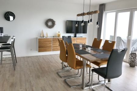 NordseeResort Friesland Ferienhäuser NordseeResort Friesland 48-6-n Schillig - Wohn-Essbereich mit Esstisch, Sitzgelegenheit und Flatscreen TV