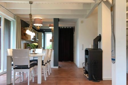 NordseeResort Friesland Ferienhäuser NordseeResort Friesland 1 Schillig - Wohn-Essbereich mit Esstisch und Kamin