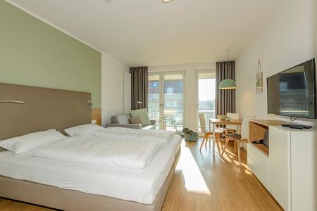 Apartmentvilla Anna See Apartmentvilla Anna See 2-06 Langeoog - Wohn-Essbereich mit Couch und Doppelbett