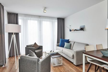Deichhäuser Anna Küste Deichhäuser Anna Küste 4-34 Bensersiel - Wohn-Essbereich mit Couch, Sessel, Esstisch und Zugang zum Balkon