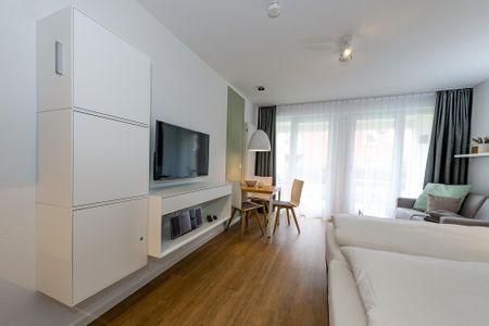 Deichhäuser Anna Küste Deichhäuser Anna Küste 6-12 Bensersiel - Wohn-Ess-Schlafbereich mit Sofa, Esstisch, und Doppelbett sowie Flatscreen TV