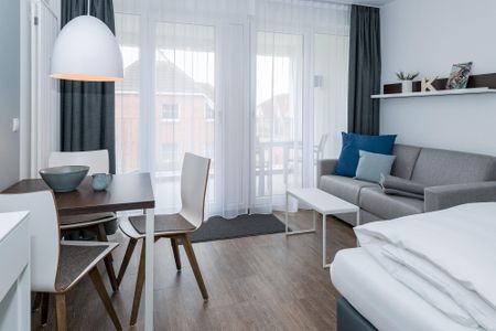 Deichhäuser Anna Küste Deichhäuser Anna Küste 6-22 Bensersiel - Wohn-Ess-Schlafbereich mit Sofa, Esstisch, Sitzgelegenheit und Doppelbett sowie Zugang zum Balkon