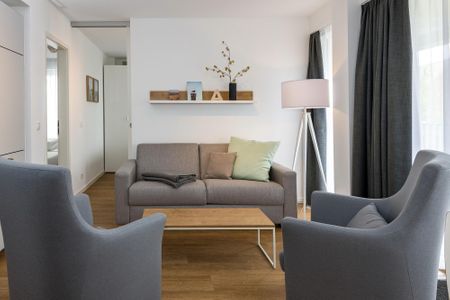 Deichhäuser Anna Küste Deichhäuser Anna Küste 6-23 Bensersiel - Wohnbereich mit Sofa, Sessel, Couchtisch und Zugang zum Balkon