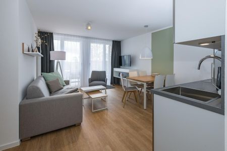 Deichhäuser Anna Küste Deichhäuser Anna Küste 6-31 Bensersiel - Wohn-Essbereich mit Couch, Esstisch, Sitzgelegenheit und Zugang zum Balkon