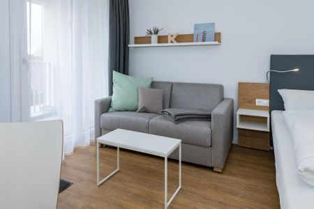 Deichhäuser Anna Küste Deichhäuser Anna Küste 6-32 Bensersiel - Wohn-Ess-Schlafbereich mit Sofa, Esstisch, Sitzgelegenheit und Doppelbett sowie Zugang zum Balkon
