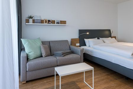 Deichhäuser Anna Küste Deichhäuser Anna Küste 8-22 Bensersiel - Wohn-Ess-Schlafbereich mit Sofa, Esstisch, Sitzgelegenheit und Doppelbett sowie Zugang zum Balkon