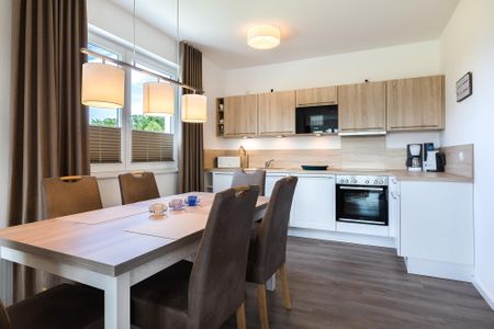 Aparthotel Ostseeallee Aparthotel Ostseeallee 3-28 Boltenhagen - Wohn-/Essbereich mit Tisch, Sitzgelegenheiten und Küchenzeile