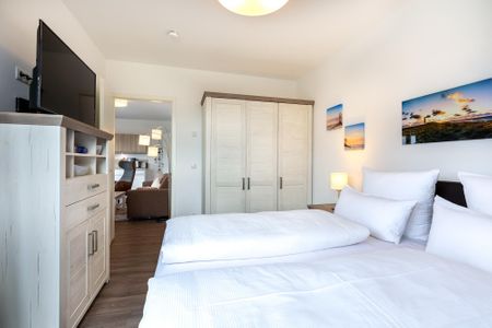 Aparthotel Ostseeallee Aparthotel Ostseeallee 4-38 Boltenhagen - Schlafzimmer mit Boxspringbett, Kleiderschrank, TV und Blick zum Wohn-/Essbereich