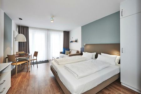 Deichhäuser Anna Küste Deichhäuser Anna Küste 4-32 Bensersiel - Wohn-Ess-Schlafbereich mit Sofa, Esstisch, Sitzgelegenheit und Doppelbett sowie Zugang zum Balkon