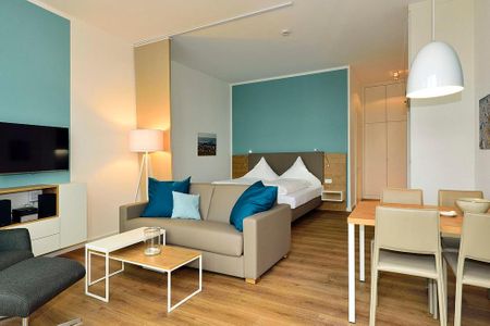 Aparthotel Anna Düne Aparthotel Anna Düne 0-04 Wangerooge - Wohn/ Essbereich mit Couch, Fernseher und Esstisch