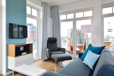 Aparthotel Anna Düne Aparthotel Anna Düne 1-12 Wangerooge - Wohn/ Essbereich mit Sessel und Fernseher