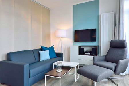Aparthotel Anna Düne Aparthotel Anna Düne 2-30 Wangerooge - Wohn/ Essbereich mit Couch, Sessel und Fernseher