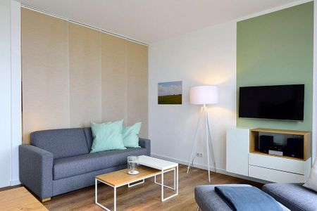 Aparthotel Anna Düne Aparthotel Anna Düne 1-23 Wangerooge - Wohn/ Essbereich mit Couch, Tisch und Fernseher