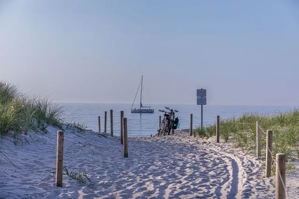Strandaufgang mit Blick auf ein Segelboot  Strandlilie