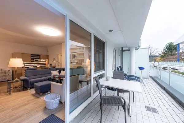 Ferienwohnung Bernstein Zingst – Großzügiger Balkon mit Sitzgruppe und Blick ins Wohnzimmer durch bodentiefe Schiebetür  Bernstein