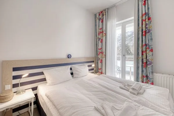 Ferienwohnung Bernstein Zingst – Helles Schlafzimmer mit Doppelbett, maritimer Holz-Kopfteilgestaltung  Bernstein