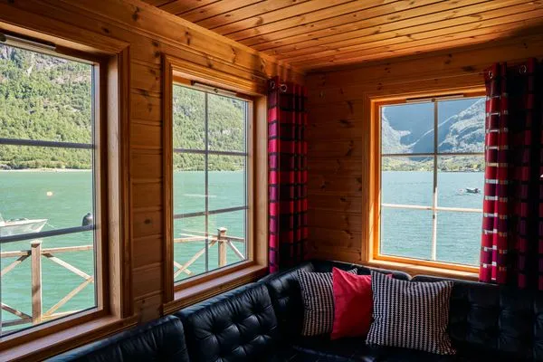 Blick durch die Fenster auf smaragdgrünes Wasser des Fjords direkt vor dem Ferienhas  Fjordhytte-4