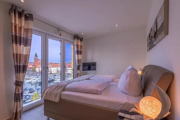 ChatGPT:  Ferienwohnung Garzini Hafenresidenz Waren (Müritz) – Helles Schlafzimmer mit Panoramafenstern  Garzini