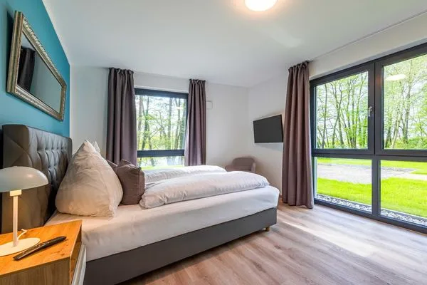 Apartment Yoga-Oase Krakow am See – Schlafzimmer mit sanften Farben und große Fenster mit Naturblick  Yoga-Oase