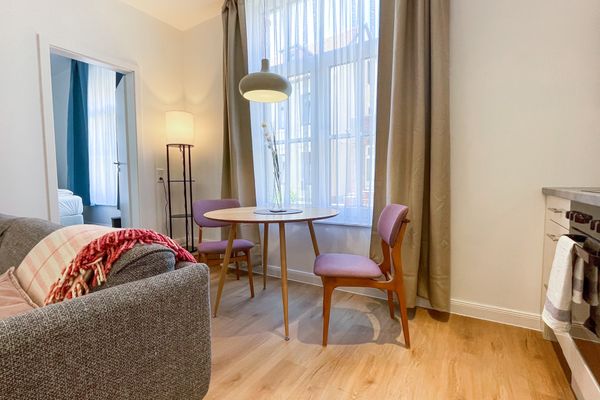  Haus Derk Juist - Wohnung 12 Borkum - Blick auf Sofa und Esstisch mit zwei Stühlen
