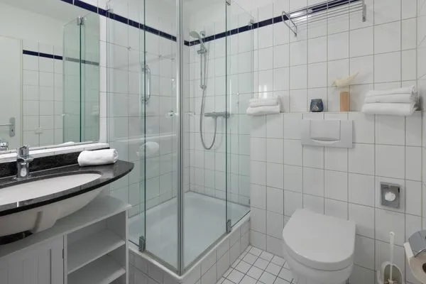Ferienwohnung Godewind Aparthotel Zingst - Blick ins Badezimmer mit Glasdusche, Waschbecken und Toilette  Godewind