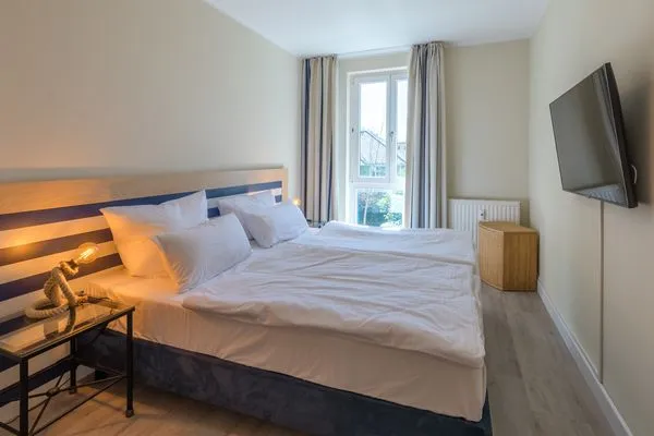 Ferienwohnung Godewind Aparthotel Zingst - helles Schlafzimmer mit gemütlichem Doppelbett und Fenster  Godewind