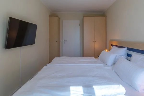 Ferienwohnung Godewind Aparthotel Zingst - Blick ins Schlafzimmer mit Doppelbett, TV und Kleiderschränken  Godewind