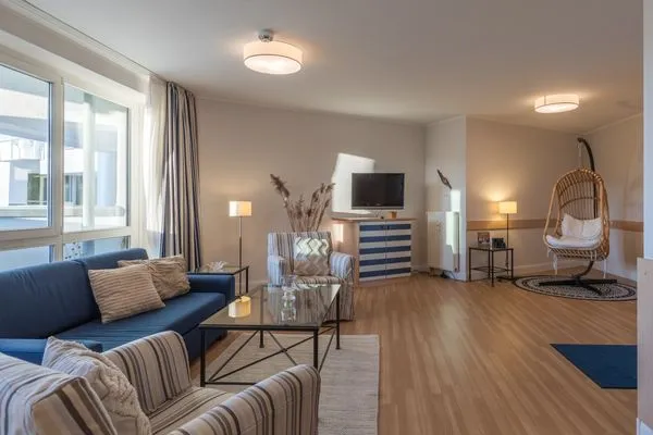 Ferienwohnung Kranichtanz Aparthotel Zingst - Blick ins helle und offene Wohnzimmer mit Couch und Sesseln  Kranichtanz