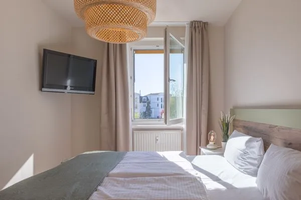 Ferienwohnung Küstenglück Aparthotel Zingst - Blick aus dem fenster des Schlafzimmers und Doppelbett mit TV  Küstenglück