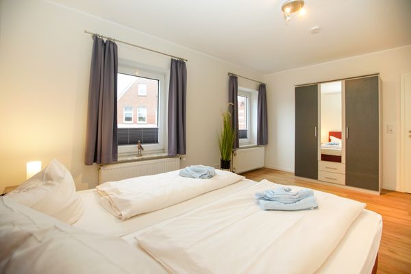  Haus Derk Juist - Wohnung 3 Borkum - Zweites Schlafzimmer, Blick vom Bett zum Schrank und zu den Fenstern