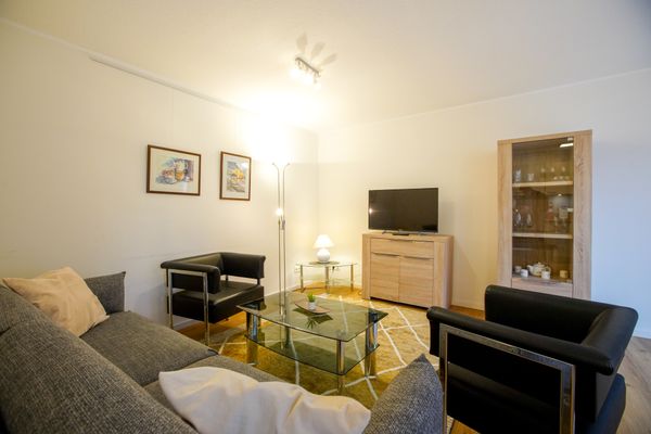  Haus Derk Juist - Wohnung 3 Borkum - Wohnzimmerecke mit Sofa, Sesseln und Kommode mit TV