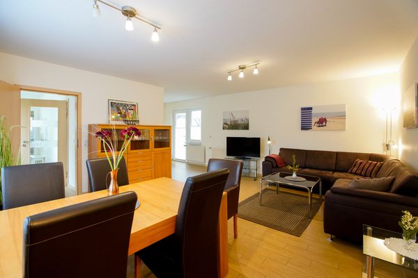  Haus Derk Juist - Bungalow Borkum - Wohnzimmer mit Blick auf Esstisch, Sideboard, TV und Sofa, in Richtung Terrassentür