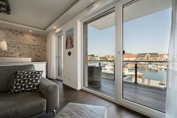 Ferienwohnung First Marina View Waren (Müritz) - Wohnbereich mit Zugang zum Balkon und Hafenblick  First Marina View