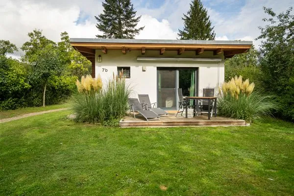 Ferienhaus Kleine Sommerliebe Waren (Müritz) - Holzterrasse mit Gartenmöbeln und Liegestühlen umgeben von Ziergräsern  Kleine Sommerliebe