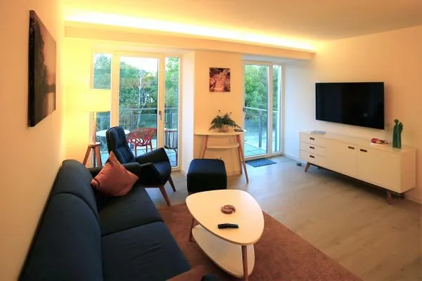 Wohn/Essbereich: Sofa, Sessel, TV, Zugang zum Balkon  FeWo room-of-light in PRORA - 9.34
