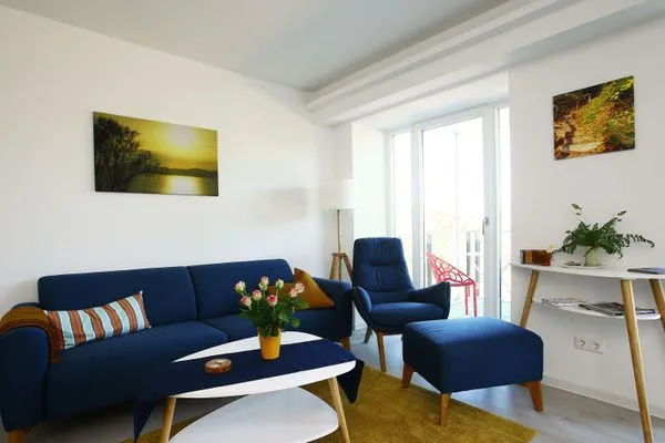 Wohn/Essbereich: Sofa, Sessel, TV, Zugang zum Balkon  FeWo room-of-light in PRORA - 9.34