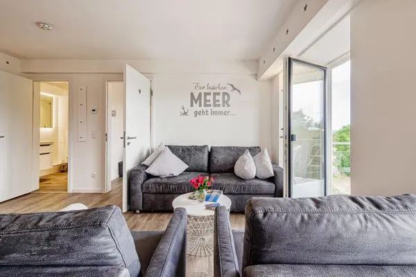 Wohn/Essbereich: Sofa, Sitzbereich, Essbereich, TV, Zugang zum Balkon  FeWo Auszeit in PRORA - 9.42