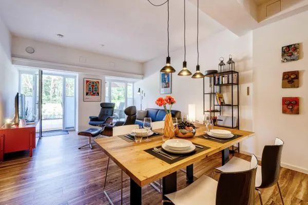 Offener Wohnbereich mit Zugang zur Terrasse, integrierter Küche, Esstisch, ausziehbarer Couch, Relaxsesseln, Smart-TV  FeWo Dünenterrasse in PRORA - 9.04