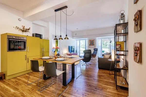 Offener Wohnbereich mit Zugang zur Terrasse, integrierter Küche, Esstisch, ausziehbarer Couch, Relaxsesseln, Smart-TV  FeWo Dünenterrasse in PRORA - 9.04