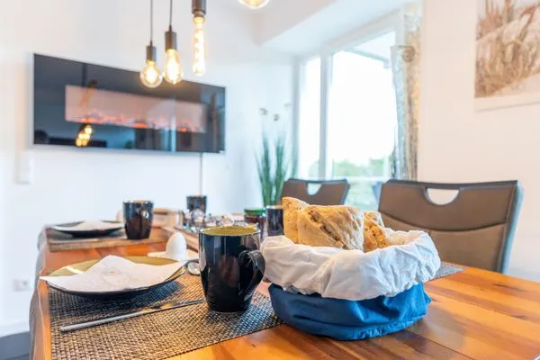 Wohn/Essbereich: Sofa, Sitzbereich, Essbereich, TV, Elektrokamin, Zugang zum Balkon  FeWo Meerlust in PRORA - 4.42