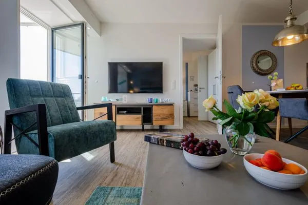 Wohnzimmer: Sofa, TV, Essbereich, Zugang zum Balkon  FeWo Strandglück in PRORA - 9.44