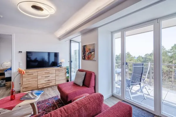 Wohnzimmer: Schlafsofa und Sessel, TV, Essbereich, Zugang zum Balkon  FeWo Seemelodie in PRORA - 9.43