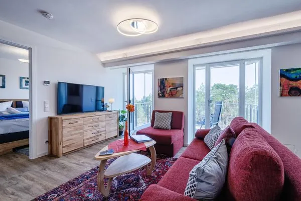 Wohnzimmer: Schlafsofa und Sessel, TV, Essbereich, Zugang zum Balkon  FeWo Seemelodie in PRORA - 9.43