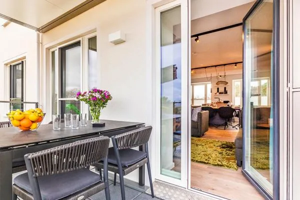 Wohn-/Essbereich: Couchgruppe mit Tisch, Smart-TV, Essbereich, Zugang zum Balkon mit Tisch und Stühlen (Seeseite), Sonne  FeWo Hideaway in PRORA - 2.45