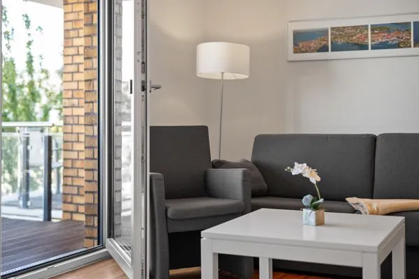 Ferienwohnung Hafenblick Waren (Müritz) – Helles Wohnzimmer mit Zugang zum Balkon und gemütlicher Sitzecke  Hafenblick