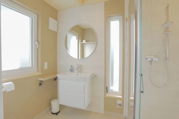Einfamilienhaus Am Hafen 21 in Zieslow — modernes Duschbad mit bodentiefer Dusche, Rundspiegel und zwei Fenstern  Am Hafen 21